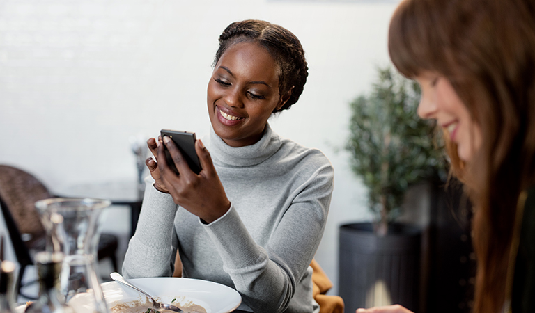 Kvinne som er ute og spiser bruker mobilen etter måltidet